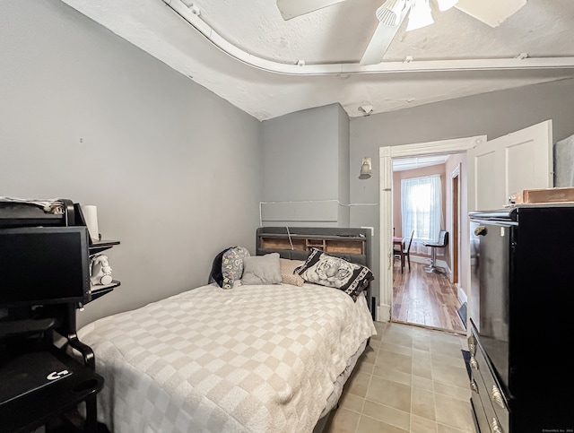 bedroom with ceiling fan, vaulted ceiling, light hardwood / wood-style floors, and a textured ceiling