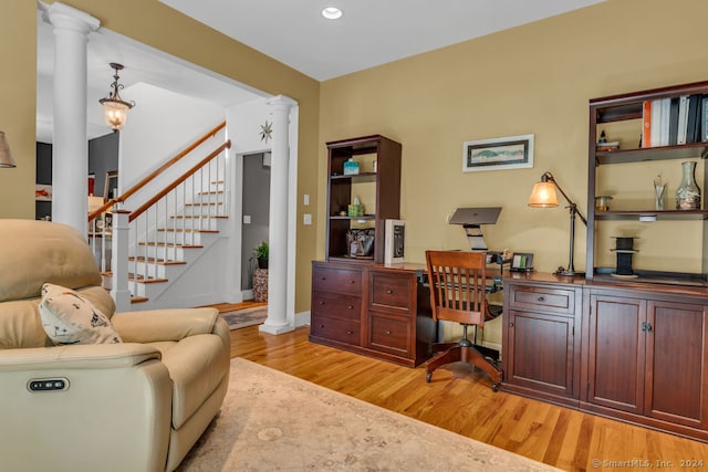 office space featuring ornate columns, built in desk, and light hardwood / wood-style floors