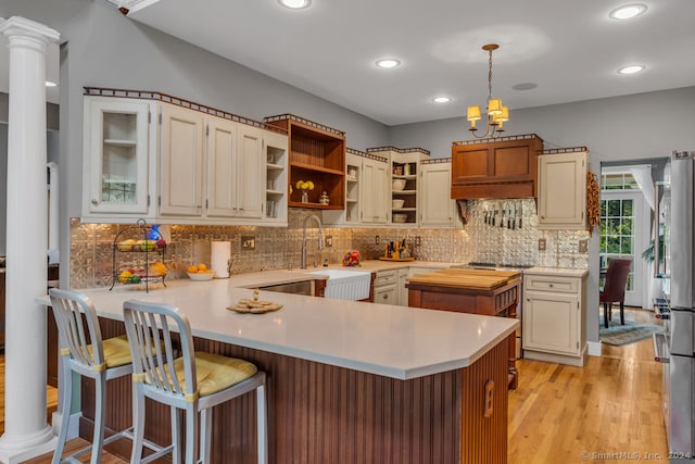 kitchen featuring tasteful backsplash, kitchen peninsula, light wood-type flooring, and a kitchen breakfast bar