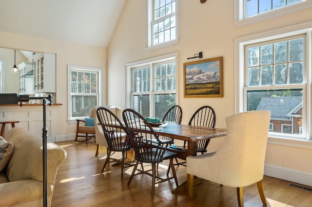 dining space with hardwood / wood-style floors and high vaulted ceiling