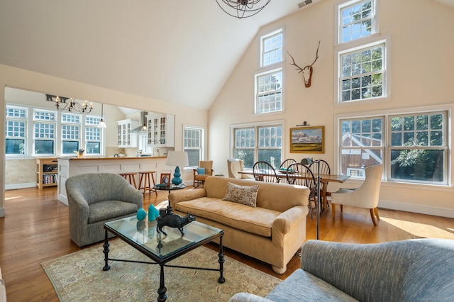 living room featuring high vaulted ceiling, a notable chandelier, and light hardwood / wood-style flooring