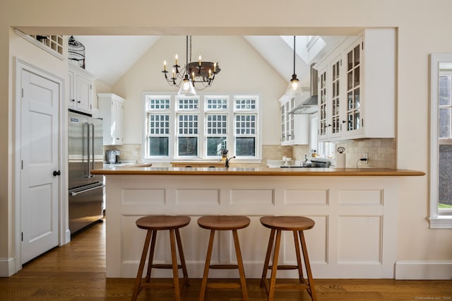 kitchen with decorative backsplash, high quality fridge, pendant lighting, and a notable chandelier