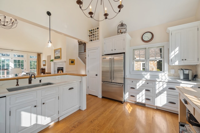 kitchen with an inviting chandelier, white cabinets, sink, and high end fridge