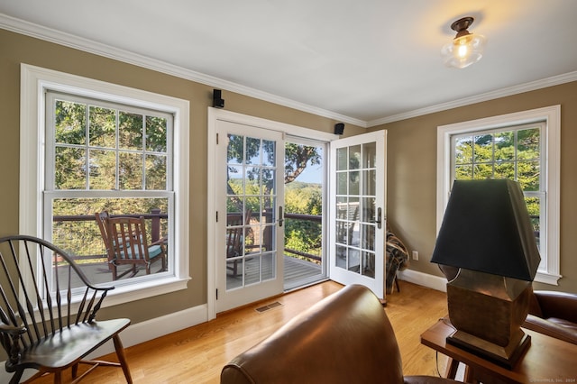 living area featuring ornamental molding, light hardwood / wood-style floors, and a wealth of natural light