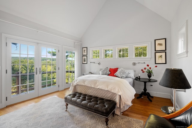 bedroom featuring access to outside, light hardwood / wood-style flooring, french doors, and high vaulted ceiling