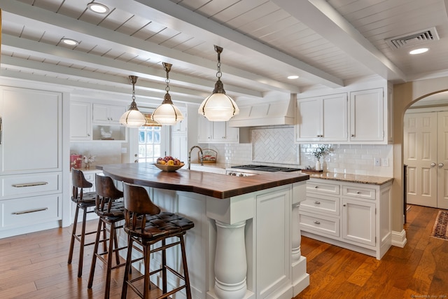 kitchen featuring dark wood-type flooring, wooden counters, white cabinetry, and a kitchen island with sink