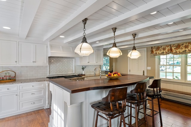 kitchen with a center island with sink, pendant lighting, dark hardwood / wood-style floors, and beam ceiling