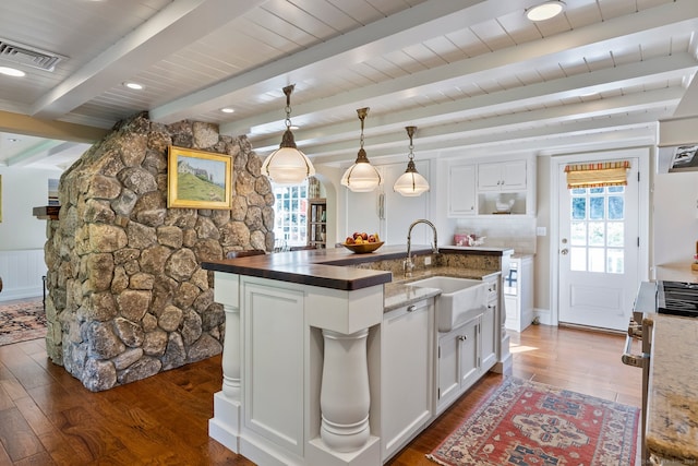 kitchen with dark wood-type flooring, pendant lighting, a center island with sink, and white cabinetry