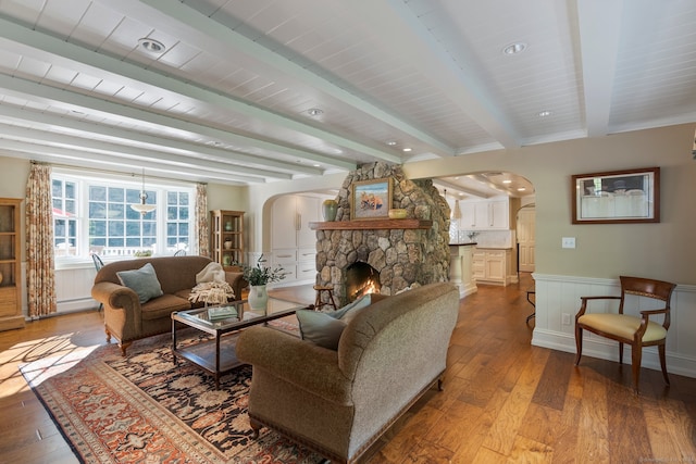 living room featuring a fireplace, beamed ceiling, and light hardwood / wood-style floors