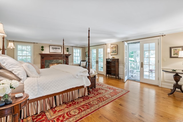 bedroom with crown molding, access to outside, french doors, and light hardwood / wood-style floors