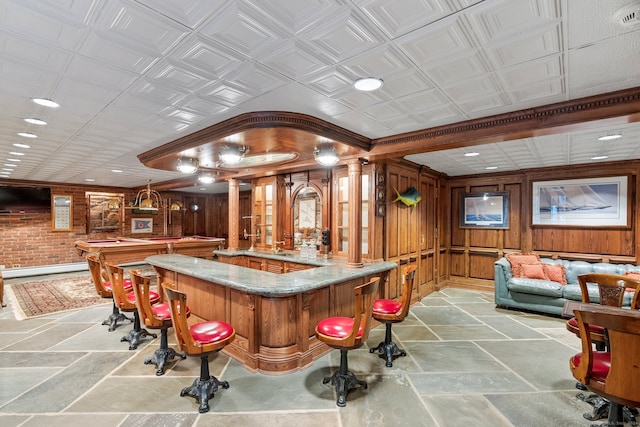 bar with light stone counters, wood walls, and decorative light fixtures