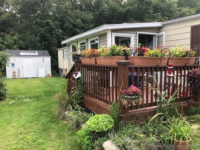 exterior space featuring a storage unit, a deck, and a yard