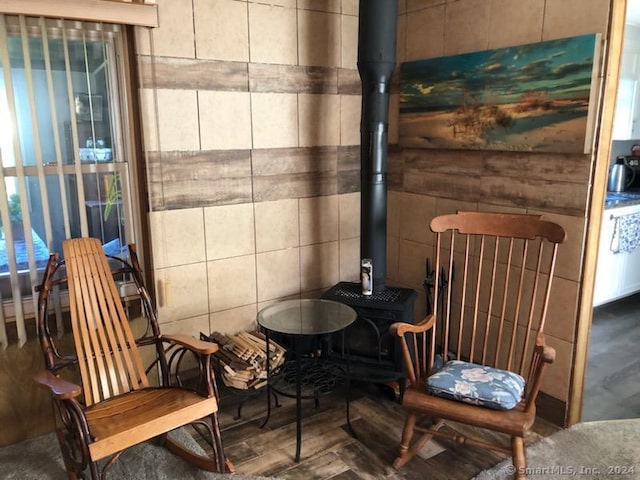 sitting room with tile walls, hardwood / wood-style floors, and a wood stove