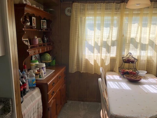 dining space with carpet flooring, wood walls, and plenty of natural light