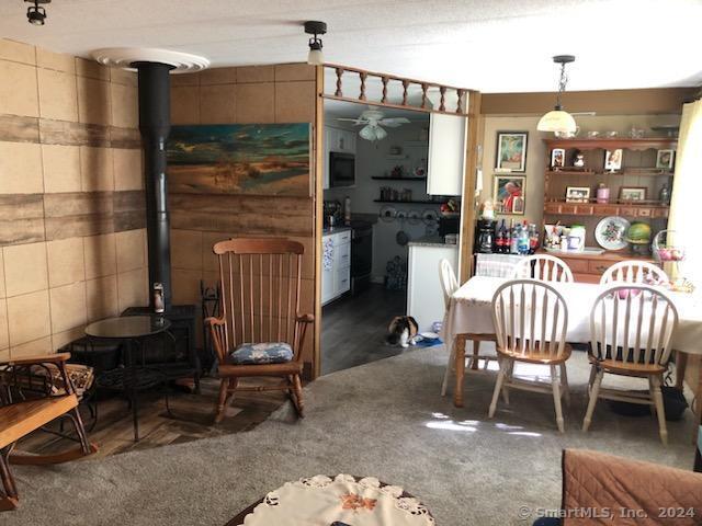 carpeted dining room featuring a wood stove