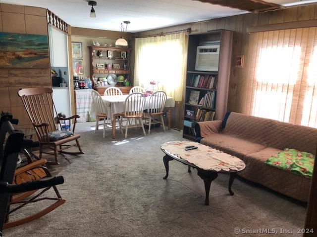 carpeted living room featuring wooden walls and a wall mounted AC