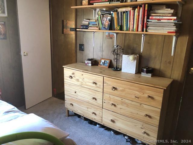 carpeted bedroom featuring wooden walls