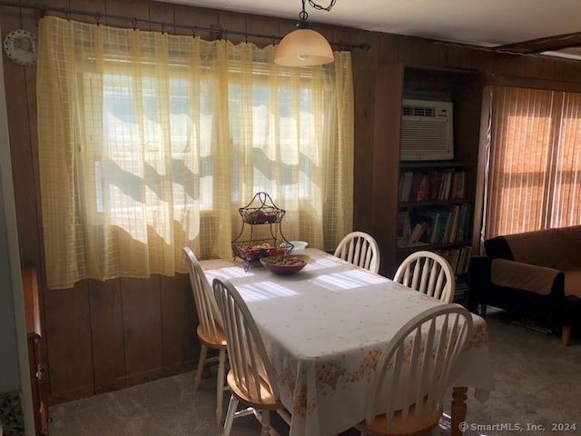 dining area featuring carpet floors and wood walls