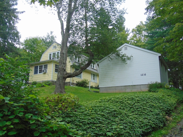 view of side of property featuring cooling unit and a yard