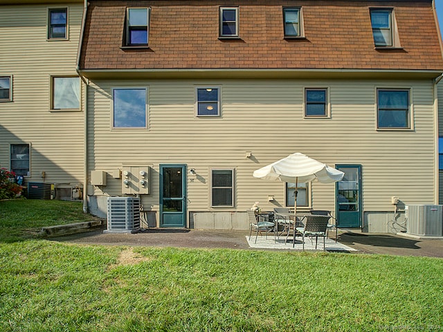 back of property with central air condition unit, a yard, and a patio