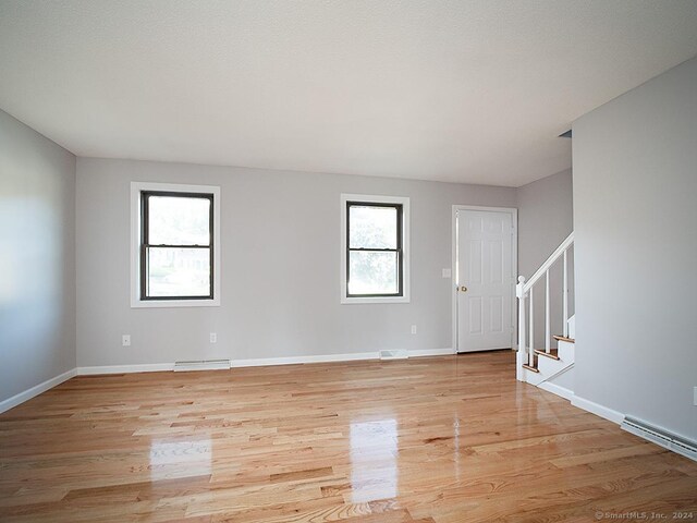 unfurnished room featuring a baseboard heating unit and light hardwood / wood-style floors