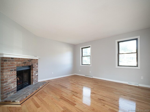 unfurnished living room with a fireplace and light wood-type flooring