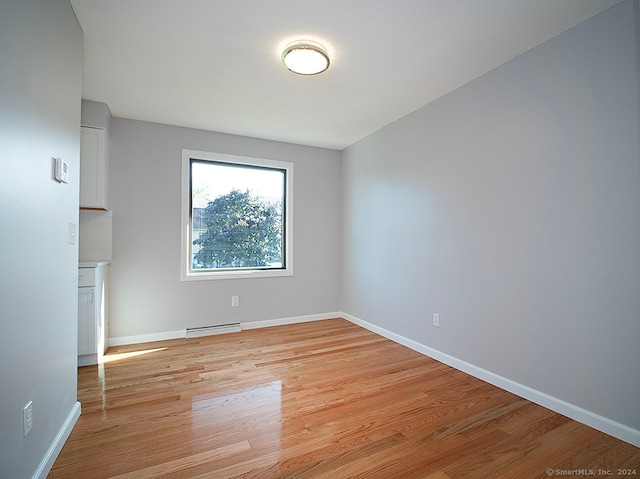 empty room with light hardwood / wood-style flooring and baseboard heating