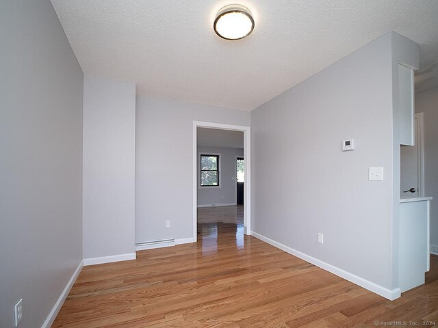 spare room with a textured ceiling, light hardwood / wood-style flooring, and a baseboard radiator