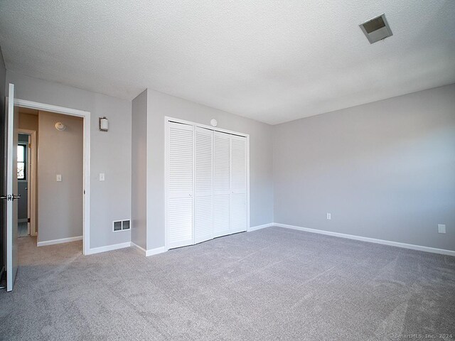 unfurnished bedroom with a closet, a textured ceiling, and carpet flooring