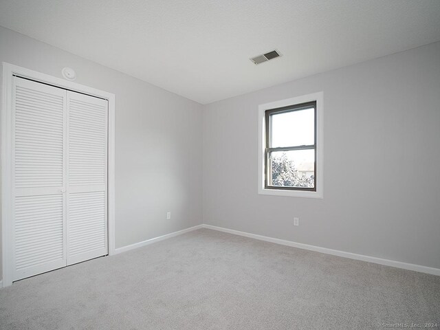 unfurnished bedroom with a closet and light colored carpet