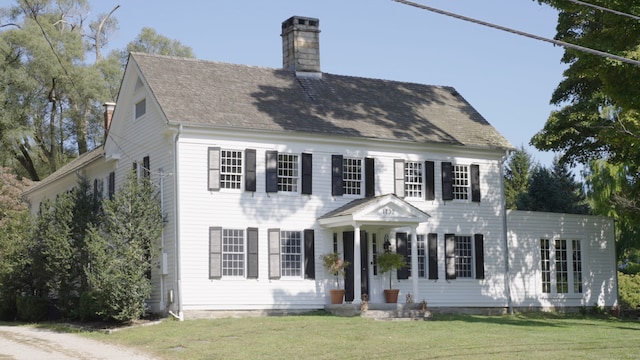 colonial-style house with a front lawn and a chimney