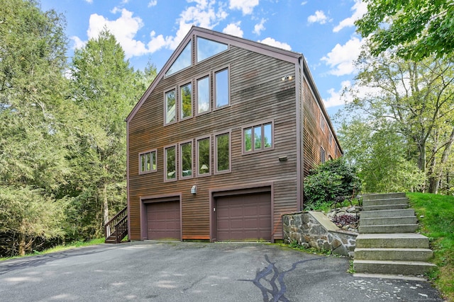 view of property exterior featuring a garage, driveway, and stairway