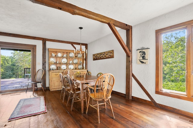 dining room featuring dark wood-type flooring, beam ceiling, visible vents, and a textured wall