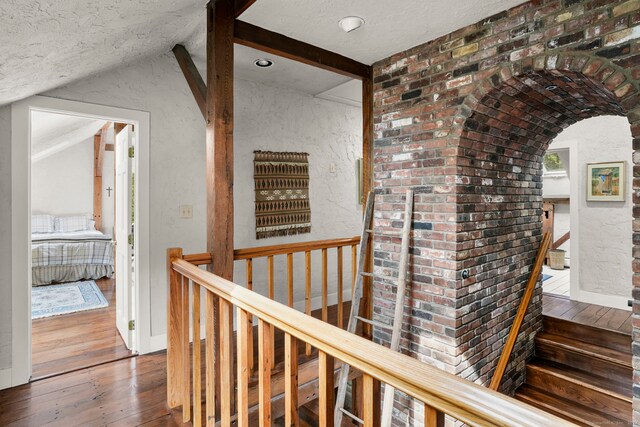 corridor featuring lofted ceiling, dark hardwood / wood-style flooring, and a textured ceiling