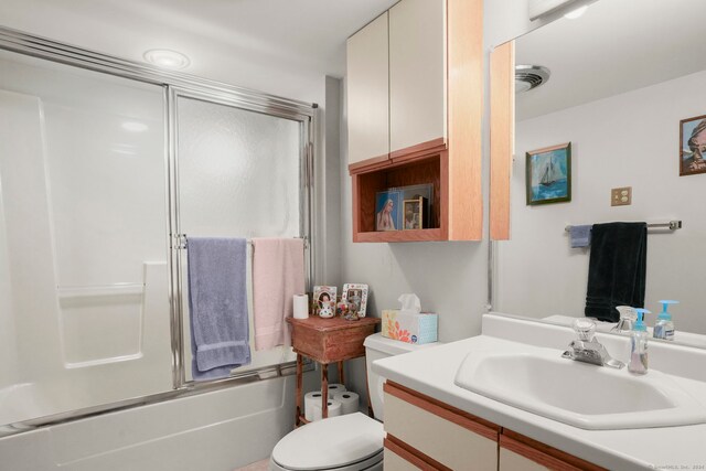 bathroom with visible vents, bath / shower combo with glass door, vanity, and toilet