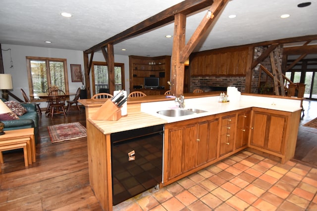 kitchen featuring a textured ceiling, a sink, open floor plan, light countertops, and beamed ceiling