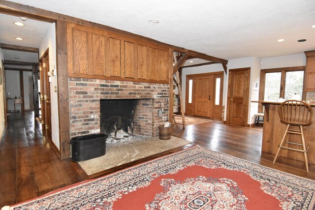 living area with dark wood-type flooring, a brick fireplace, and recessed lighting