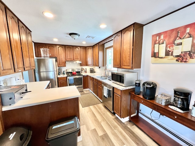 kitchen featuring kitchen peninsula, a breakfast bar area, stainless steel appliances, light wood-type flooring, and sink