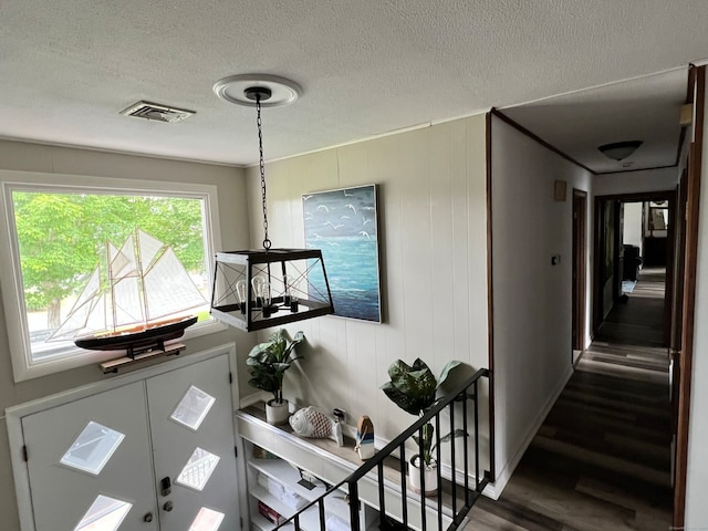 stairway with wood walls, a textured ceiling, and hardwood / wood-style floors