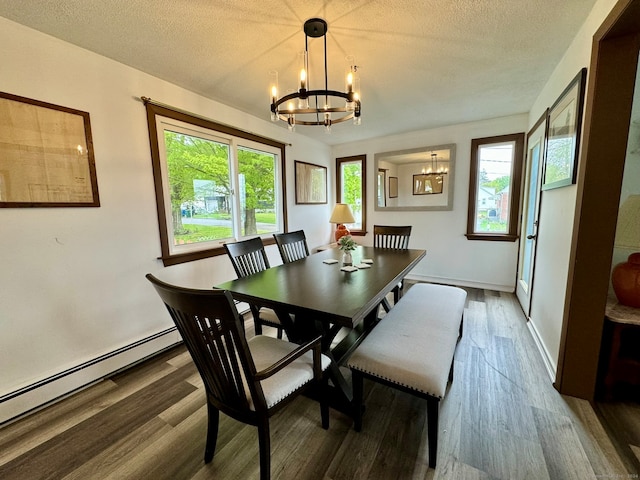 dining room with a notable chandelier, a baseboard heating unit, a textured ceiling, and dark wood-type flooring