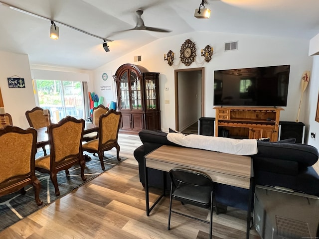 living room featuring vaulted ceiling, light hardwood / wood-style floors, track lighting, and ceiling fan