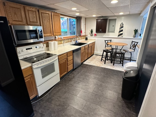 kitchen featuring electric panel, stainless steel appliances, a drop ceiling, and sink