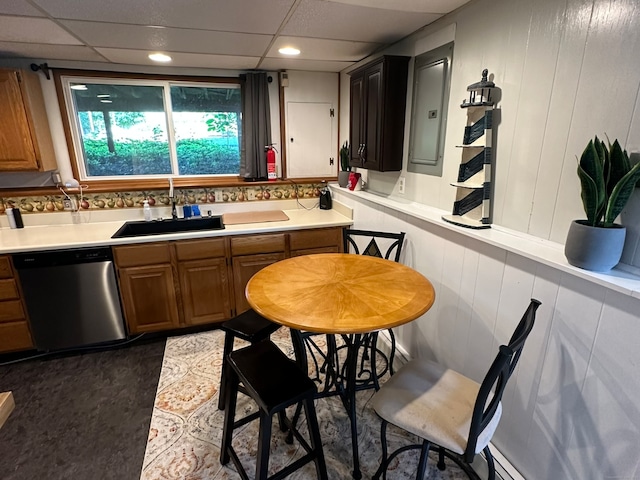 kitchen featuring wooden walls, dishwasher, sink, and a paneled ceiling