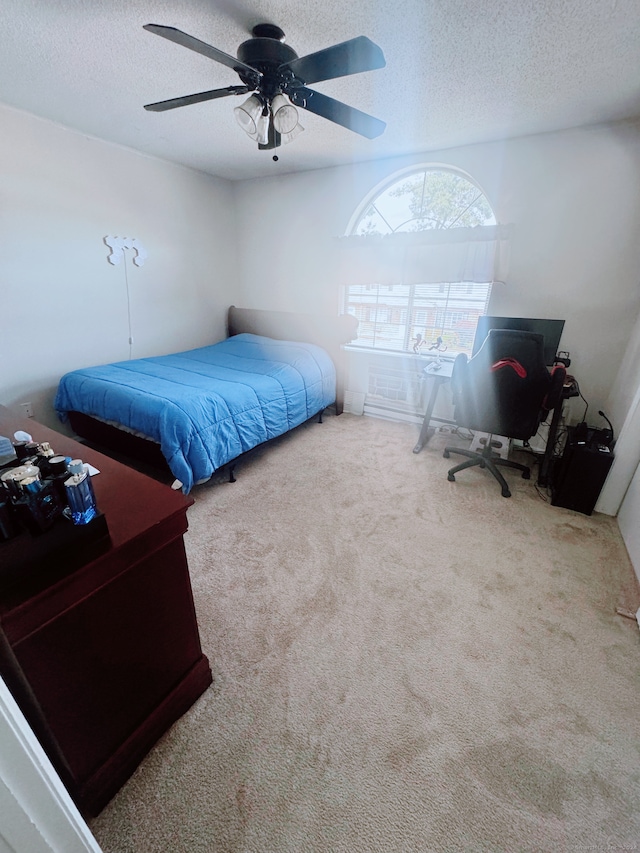 carpeted bedroom featuring ceiling fan and a textured ceiling