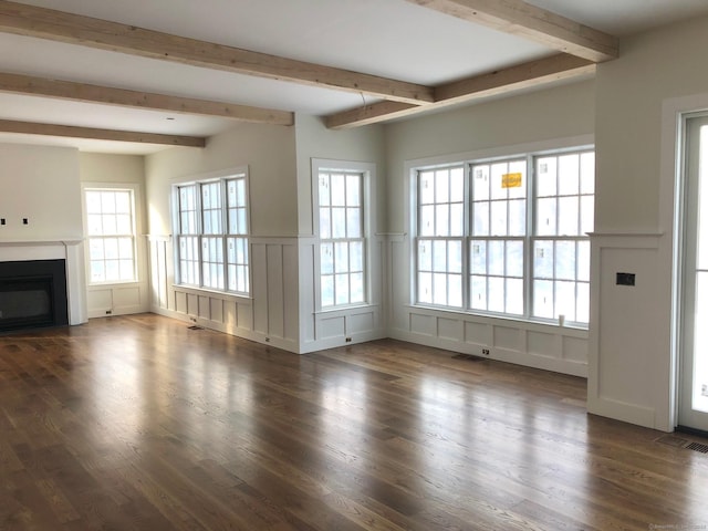 unfurnished living room featuring beamed ceiling, dark hardwood / wood-style floors, and a healthy amount of sunlight