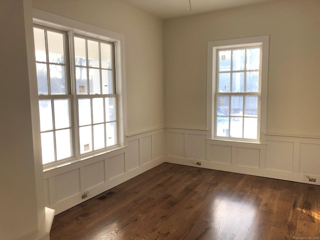 unfurnished room featuring a healthy amount of sunlight and dark hardwood / wood-style flooring