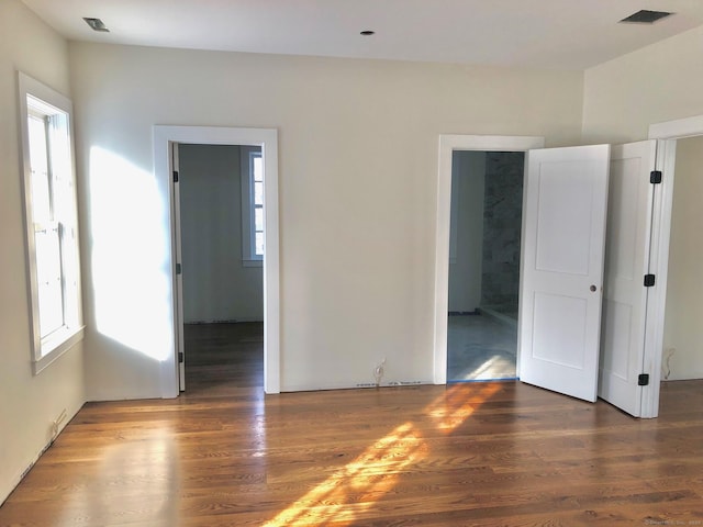 empty room featuring a healthy amount of sunlight and dark hardwood / wood-style floors