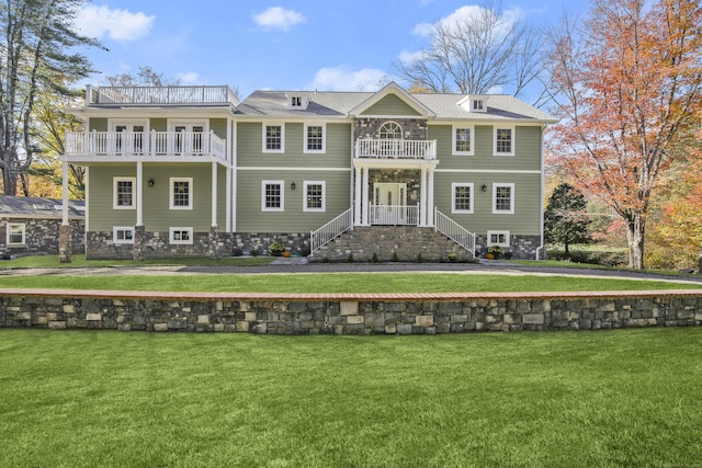 rear view of property with a yard and a balcony