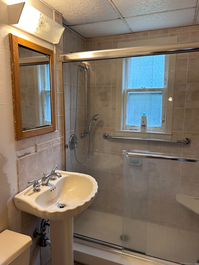 bathroom featuring a paneled ceiling, toilet, an enclosed shower, and tasteful backsplash