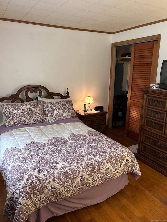 bedroom featuring a closet, wood-type flooring, and crown molding